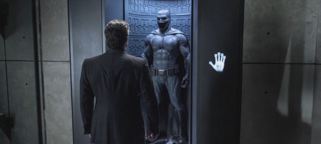 Bruce Wayne staring at his batsuit